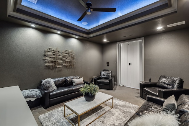 living room with visible vents, a ceiling fan, a tray ceiling, carpet, and a textured wall