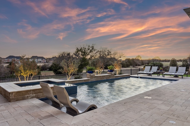 pool at dusk featuring a patio area, a fenced in pool, an in ground hot tub, and a fenced backyard