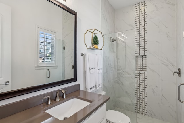 full bath with a marble finish shower, toilet, and vanity