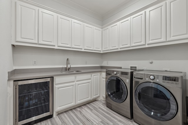 washroom with wine cooler, crown molding, washer and clothes dryer, and a sink