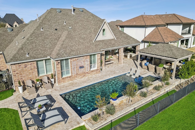 back of property featuring outdoor dry bar, brick siding, roof with shingles, a fenced backyard, and a patio