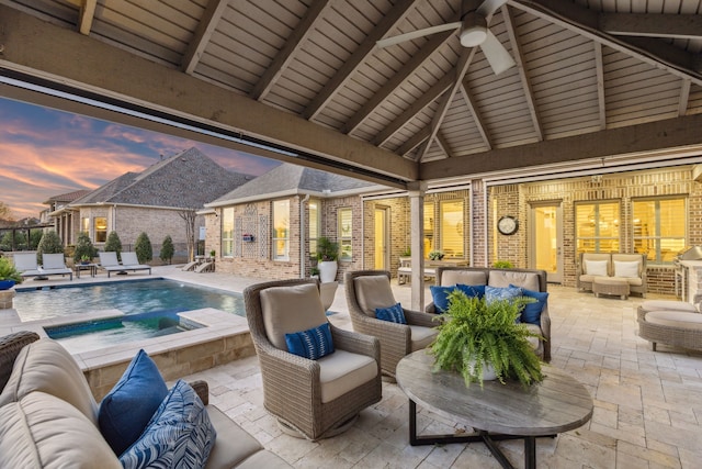 pool at dusk featuring outdoor lounge area, a patio area, an outdoor pool, and a ceiling fan