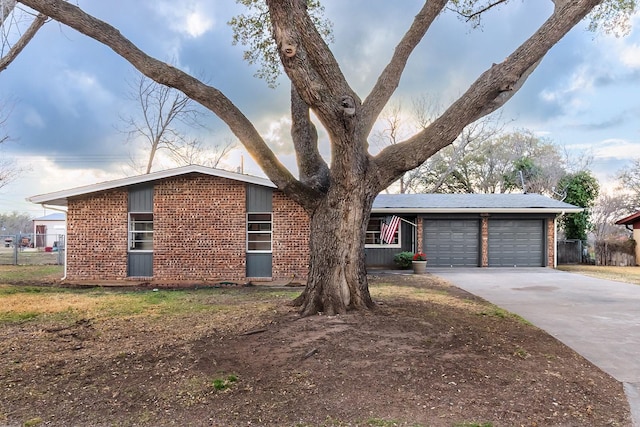 mid-century inspired home with concrete driveway, a garage, fence, and brick siding