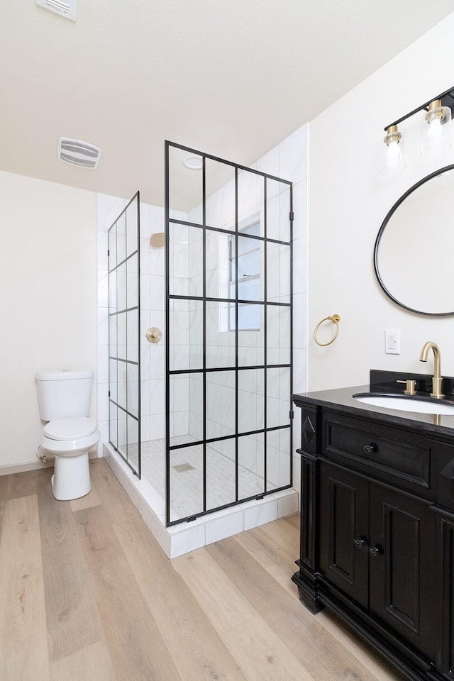2016 China, Brady, TX 76825 - full bathroom with toilet, visible vents, tiled shower, vanity, and wood finished floors