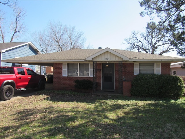 view of front facade featuring a front lawn, an attached carport, and brick siding