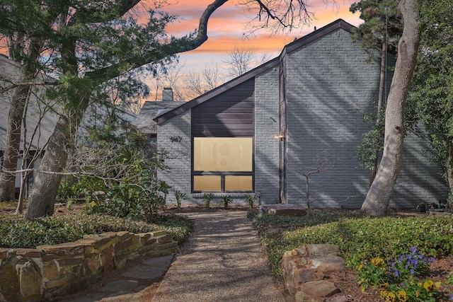 exterior space with brick siding and a chimney