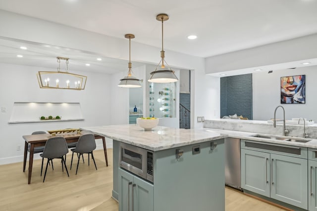 kitchen with light wood-style flooring, a sink, stainless steel microwave, recessed lighting, and light stone countertops