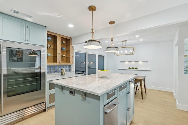 kitchen featuring visible vents, backsplash, a center island, and light wood-style floors