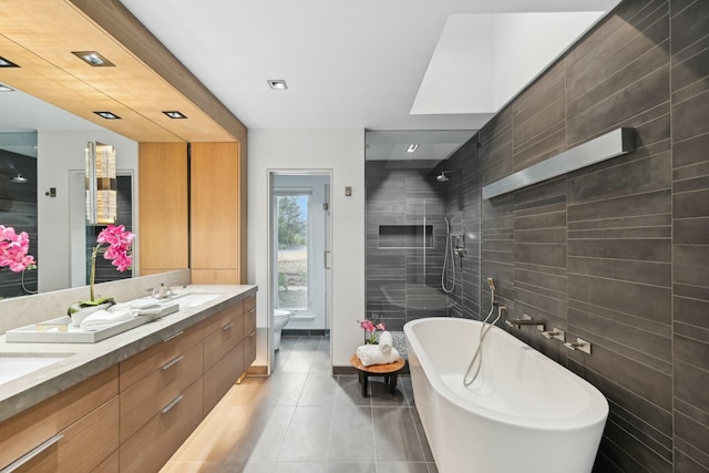 bathroom featuring double vanity, a freestanding tub, a tile shower, tile patterned floors, and toilet