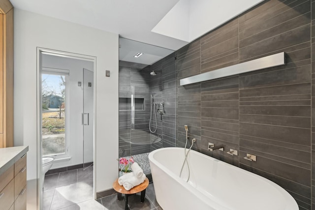 full bath with toilet, tile patterned flooring, a freestanding bath, walk in shower, and vanity