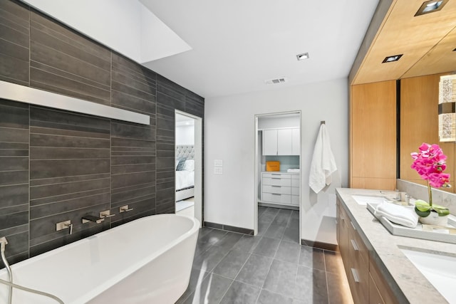 full bath with a soaking tub, double vanity, tile patterned floors, and a sink