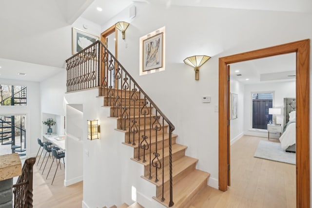 staircase with recessed lighting, baseboards, high vaulted ceiling, and wood finished floors