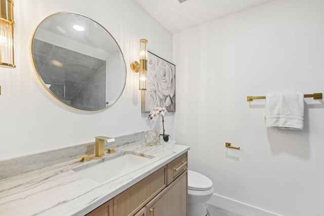 bathroom featuring baseboards, toilet, and vanity