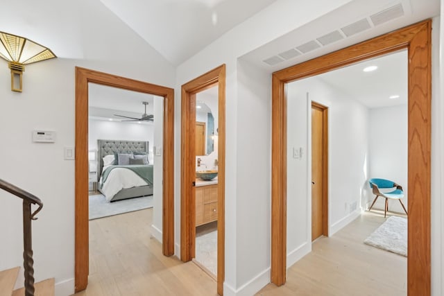 hallway with visible vents, baseboards, light wood-type flooring, recessed lighting, and a sink