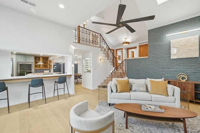 living area with stairway, light wood-type flooring, visible vents, and ceiling fan