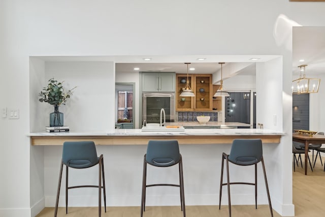 kitchen with a sink, a notable chandelier, backsplash, and a peninsula