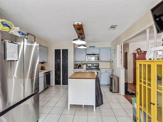 kitchen featuring light tile patterned floors, visible vents, appliances with stainless steel finishes, a textured ceiling, and butcher block counters