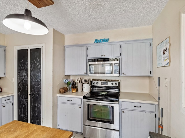 kitchen with pendant lighting, a textured ceiling, stainless steel appliances, and light countertops