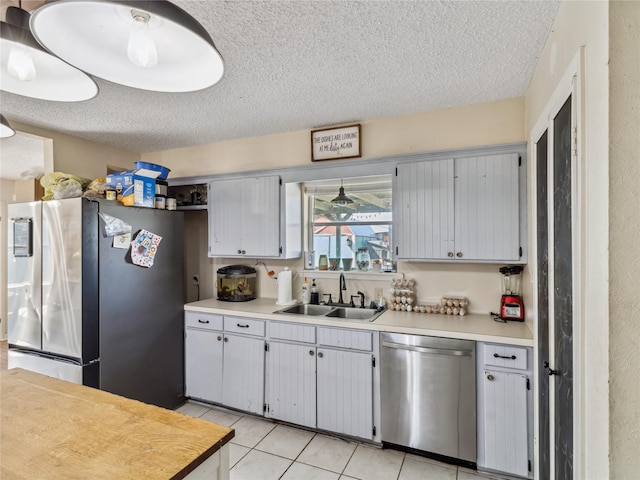 kitchen featuring a sink, appliances with stainless steel finishes, light tile patterned flooring, and light countertops