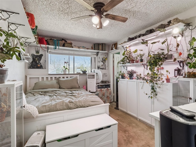 bedroom with ceiling fan, light colored carpet, and a textured ceiling