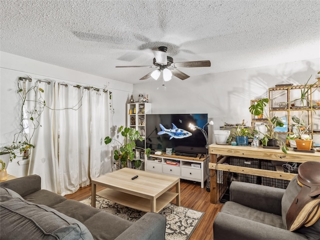 living area with a ceiling fan, wood finished floors, and a textured ceiling