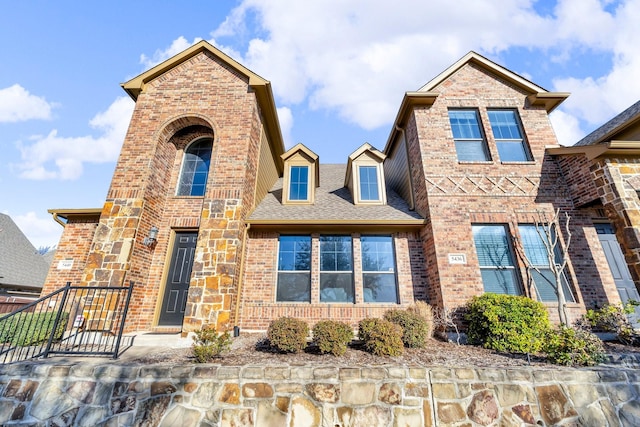 view of front of home featuring brick siding and roof with shingles