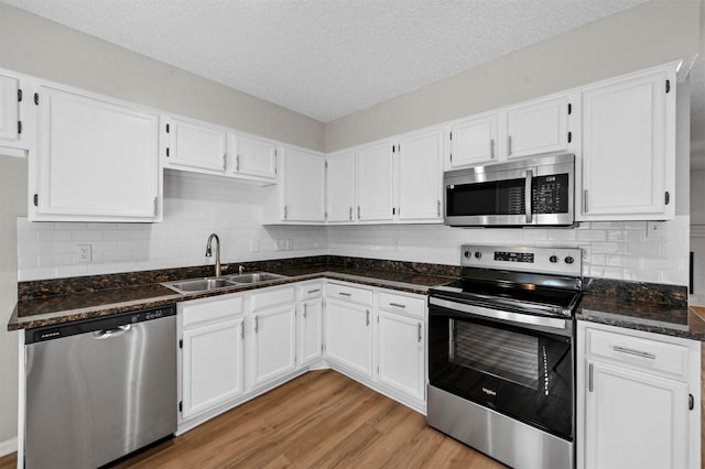 kitchen with a sink, stainless steel appliances, light wood-style floors, and white cabinetry