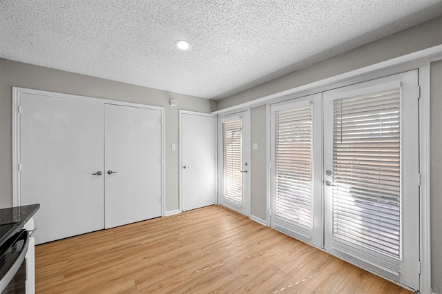 unfurnished bedroom featuring access to exterior, light wood finished floors, and a textured ceiling