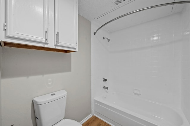 bathroom featuring a textured ceiling, toilet, bathtub / shower combination, and wood finished floors