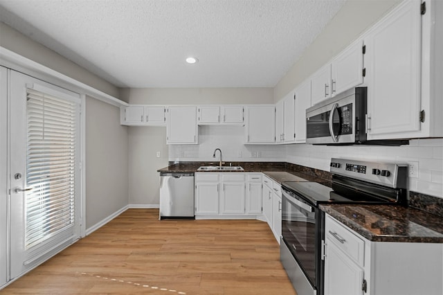 kitchen with a sink, appliances with stainless steel finishes, light wood-style flooring, and white cabinetry