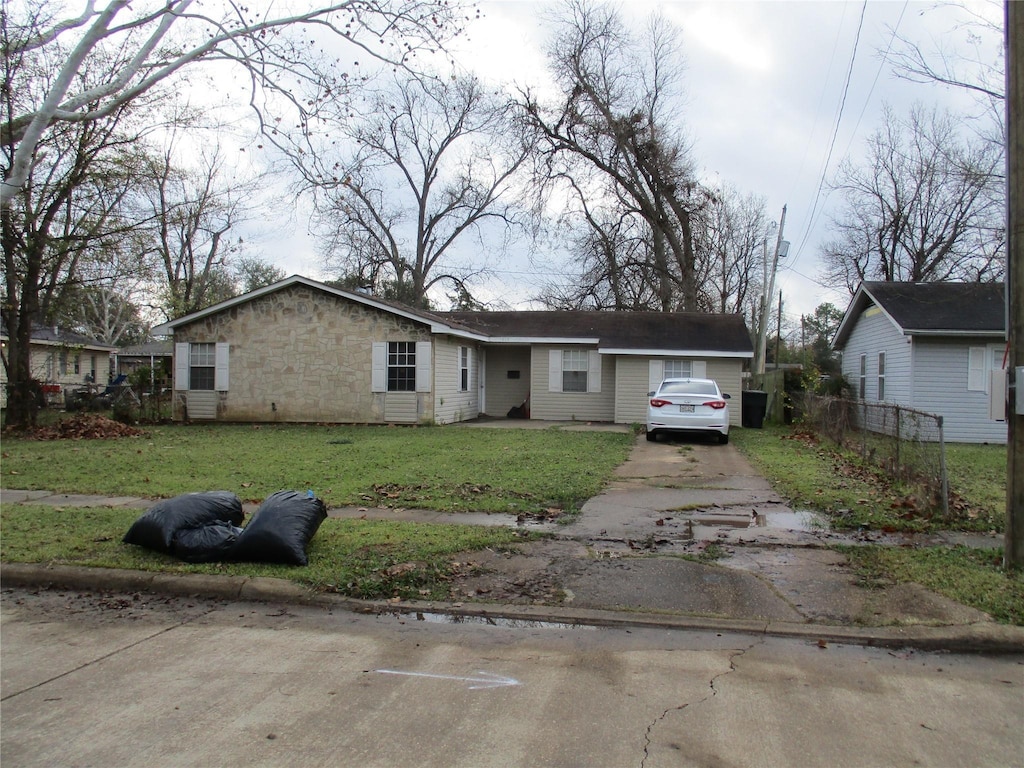 view of front of home with stone siding, a front yard, and driveway