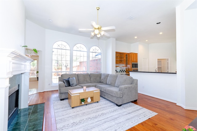 living room with wood finished floors, recessed lighting, a fireplace, baseboards, and ceiling fan