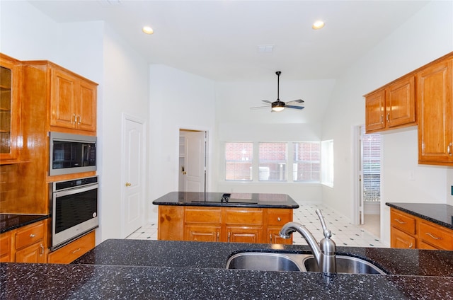 kitchen featuring brown cabinetry, built in microwave, a sink, ceiling fan, and oven