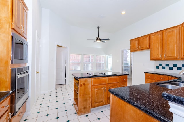 kitchen with dark stone counters, decorative backsplash, appliances with stainless steel finishes, a ceiling fan, and a sink