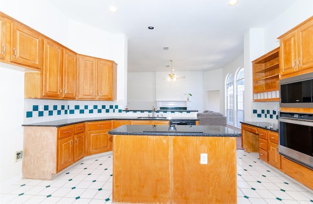 kitchen featuring dark stone countertops, a peninsula, tasteful backsplash, and a sink