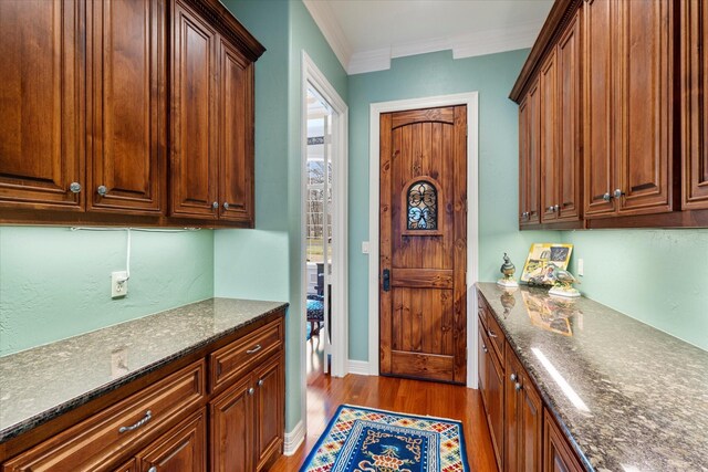 kitchen with dark stone countertops, baseboards, ornamental molding, and dark wood-style flooring