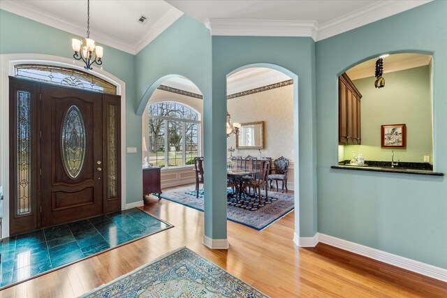 foyer featuring baseboards, a notable chandelier, wood finished floors, and crown molding