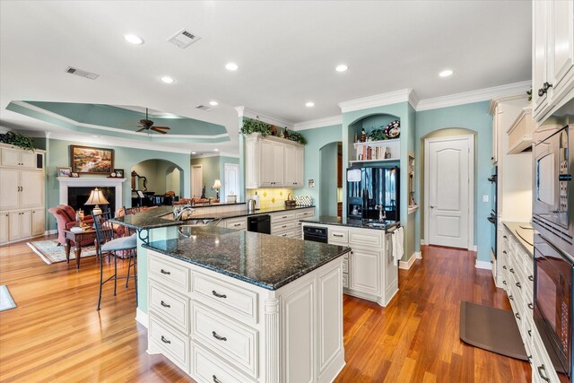 kitchen with arched walkways, visible vents, a fireplace, and a kitchen bar