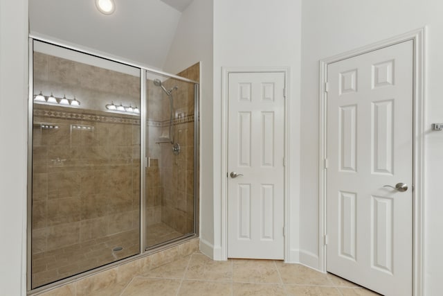 bathroom featuring lofted ceiling, tile patterned floors, and a shower stall