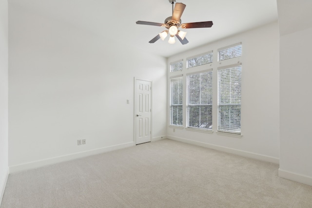 carpeted spare room with baseboards and a ceiling fan