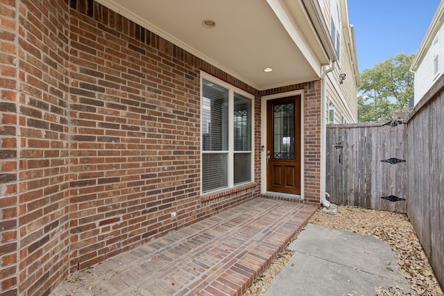 doorway to property featuring brick siding and fence