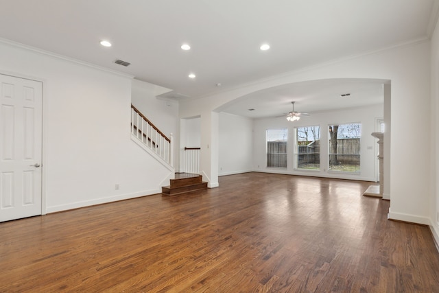 unfurnished living room with visible vents, wood finished floors, stairway, arched walkways, and crown molding