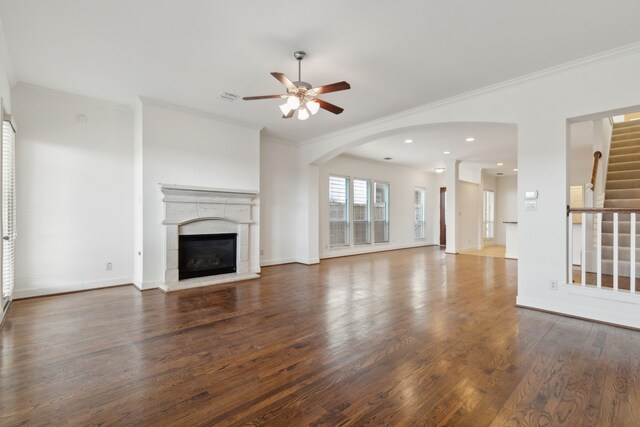 unfurnished living room with visible vents, a glass covered fireplace, wood finished floors, crown molding, and stairs