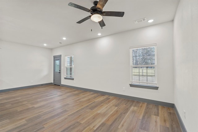 spare room featuring wood finished floors, recessed lighting, a healthy amount of sunlight, and baseboards