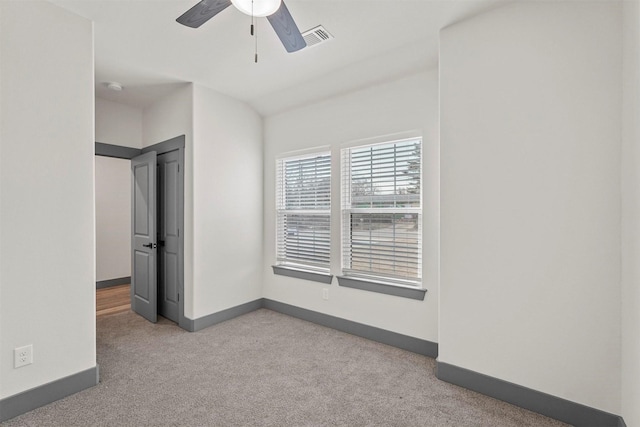 spare room with carpet flooring, baseboards, visible vents, and ceiling fan