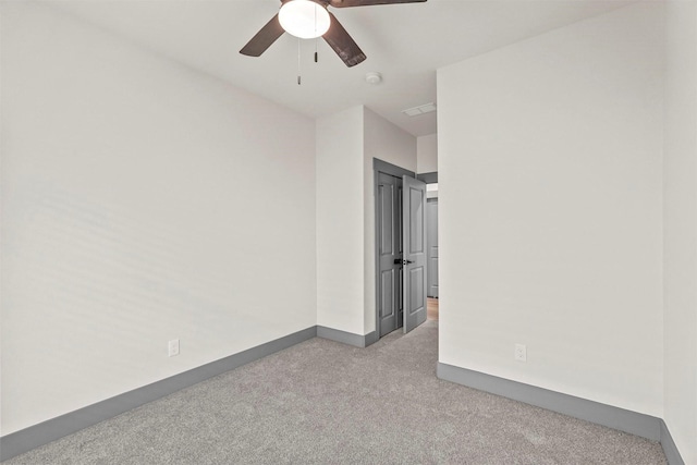 carpeted spare room featuring baseboards and ceiling fan