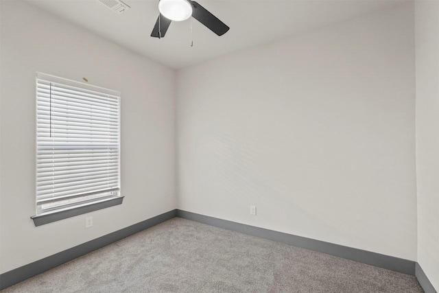 carpeted spare room with baseboards, visible vents, and ceiling fan