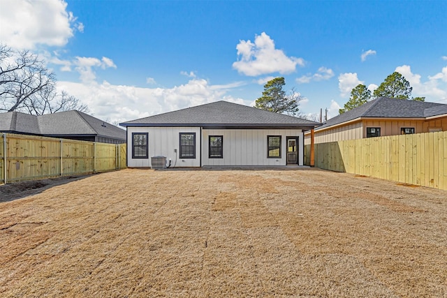 back of house with a fenced backyard and central AC