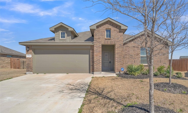 view of front of house featuring brick siding, concrete driveway, an attached garage, and fence