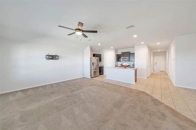 unfurnished living room with visible vents, a ceiling fan, recessed lighting, light tile patterned floors, and light colored carpet